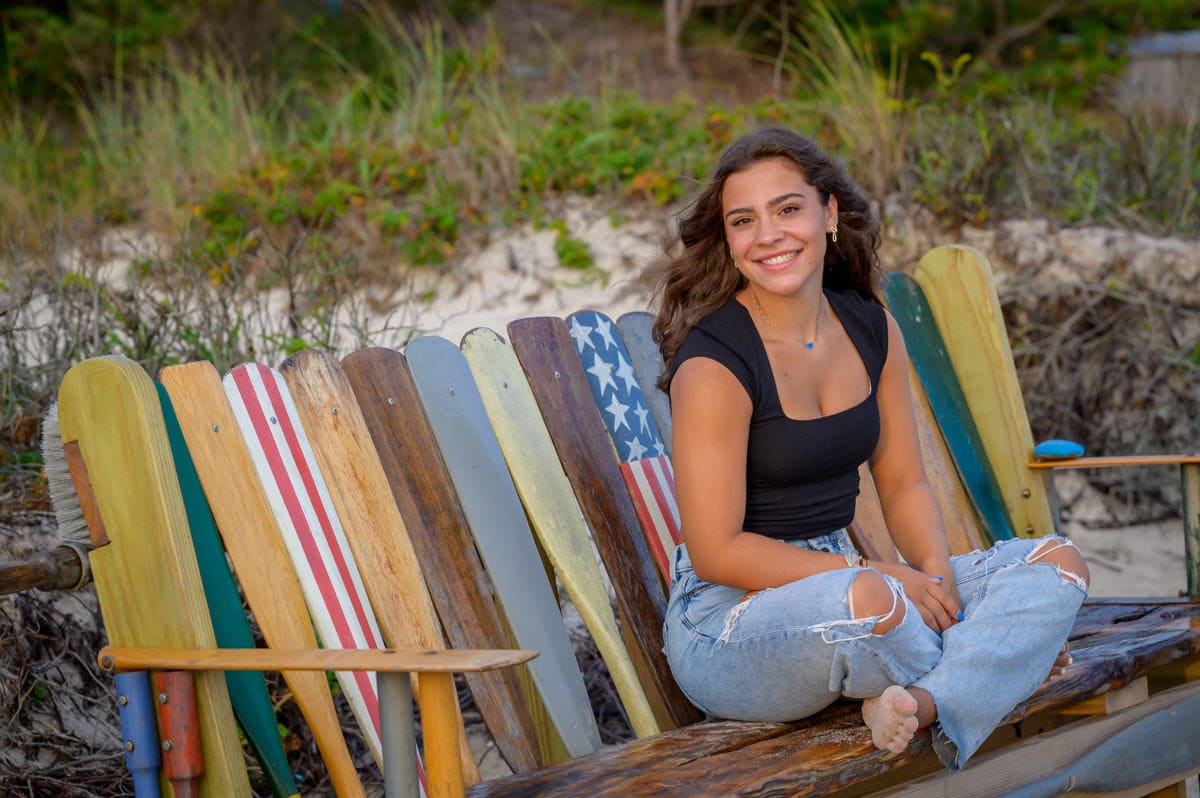anna sitting on a custom bench at the beach in centerville