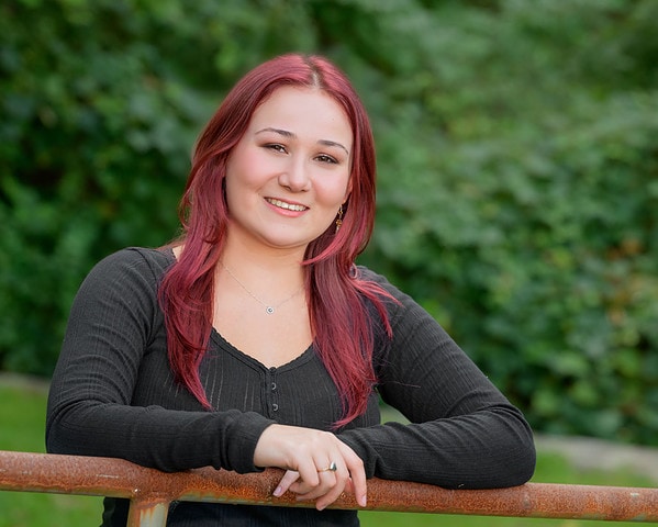 high school senior girl posing on a gate at a park in bourne at her senior portrait session