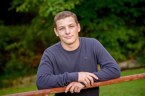 senior boy posing on a fence in a park in bourne, ma